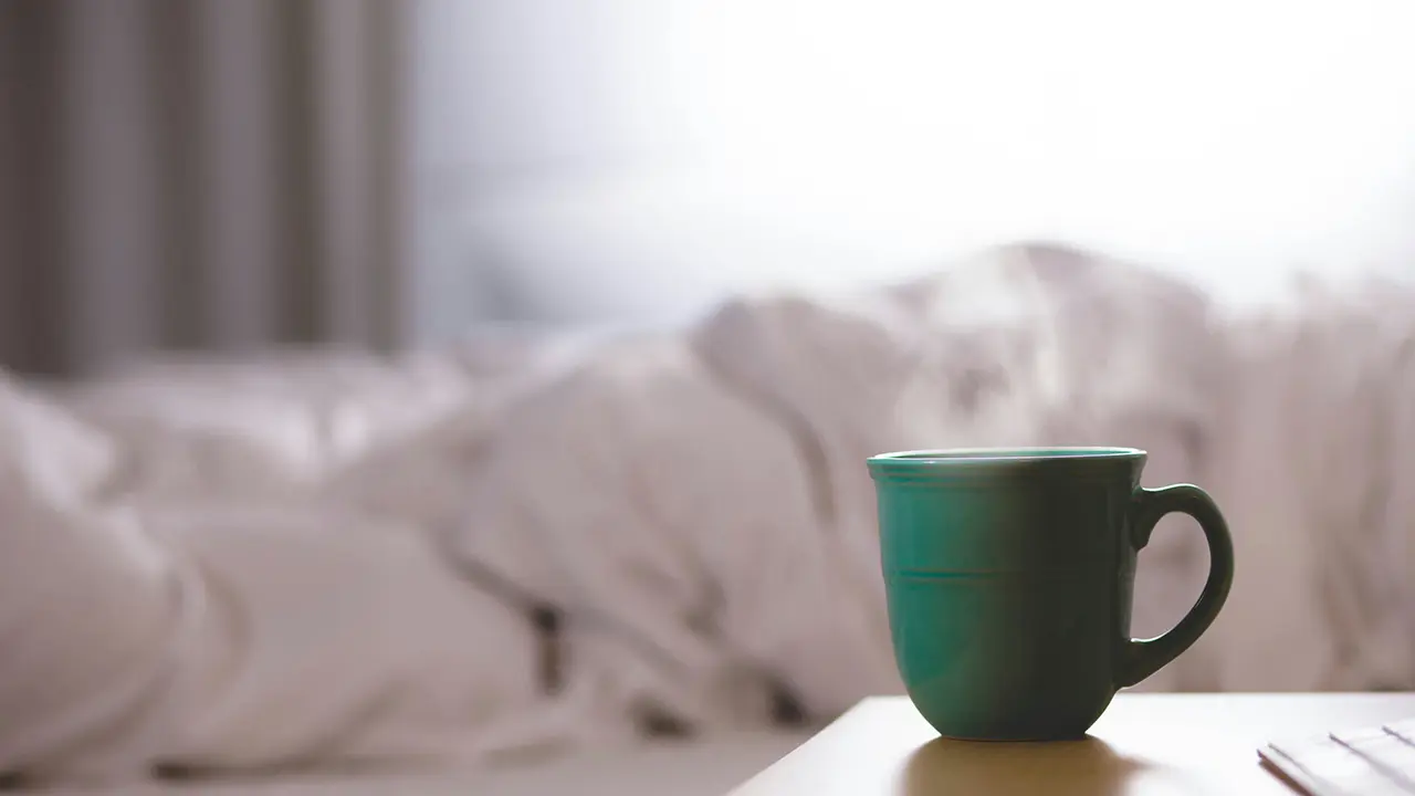 Ein dampfender Kaffeebecher auf einem Nachttisch