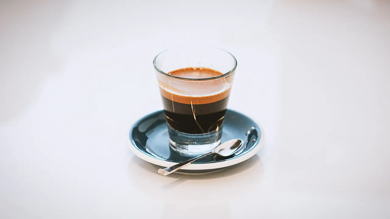 Ein gefülltes Espressoglas auf einer Untertasse