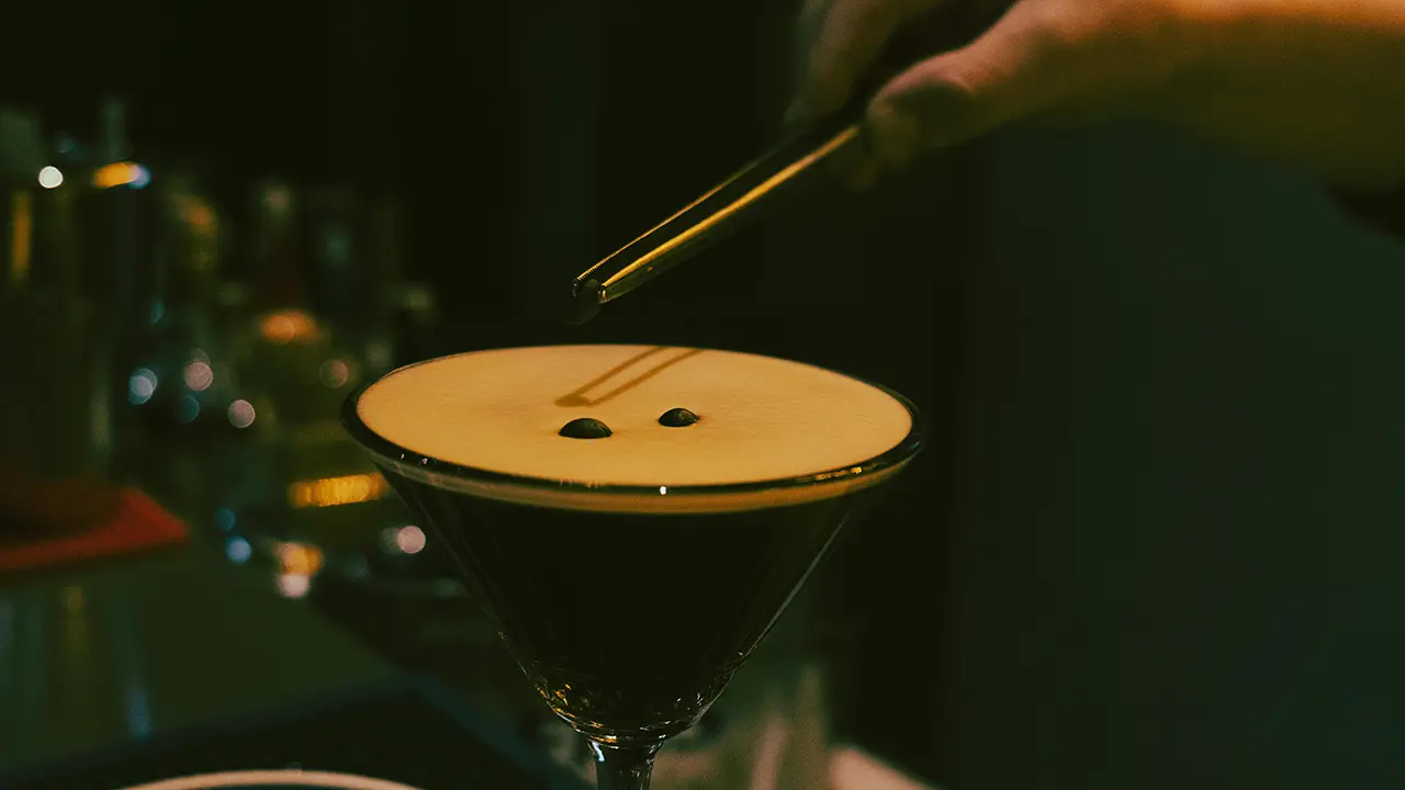 Ein Espresso Martini wird mit Kaffeebohnen dekoriert.