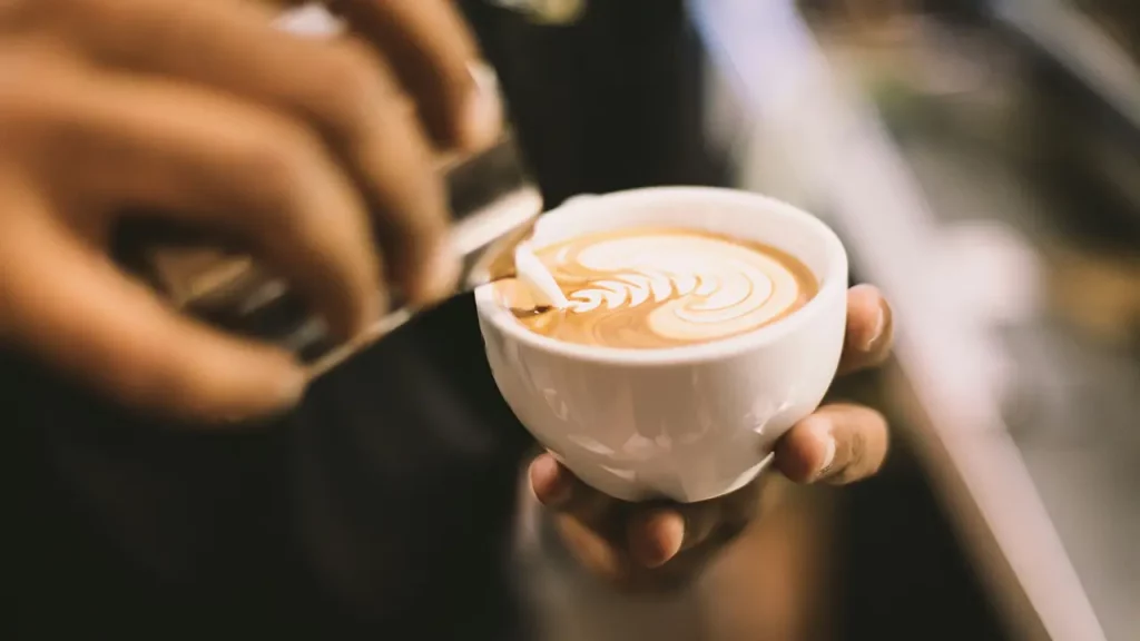 Milch wir als Latte Art in einen Cappuccino gegeben