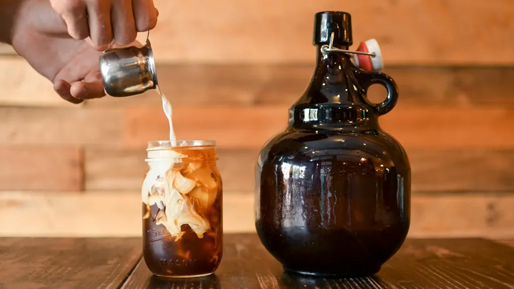 Ein Glas Cold Brew Coffee in das Milch gegossen wird.