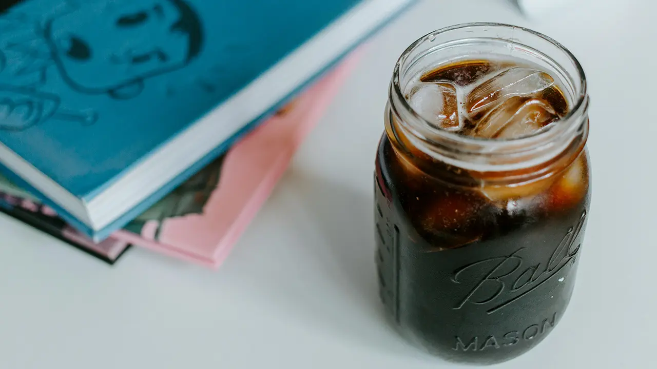 Ein Glas Cold Brew Coffee auf einem Tisch neben zwei Büchern