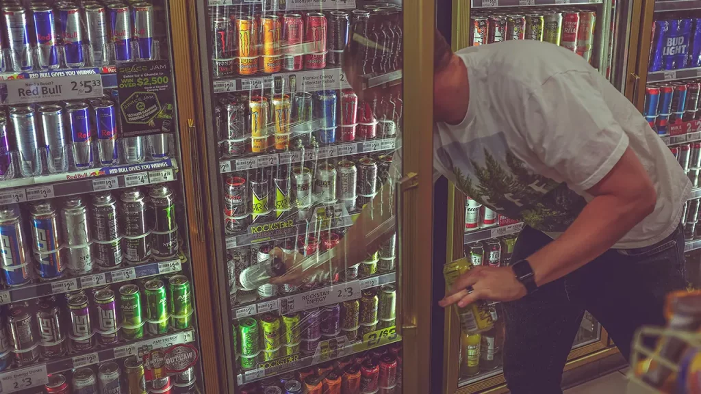 Ein Mann greift in ein Kühlregal voll mit Energy Drinks