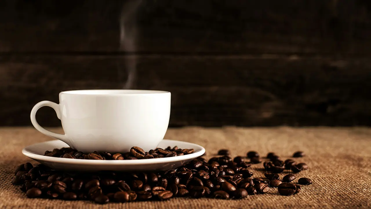 Eine Tasse Kaffee und Kaffeebohnen auf einem Tisch